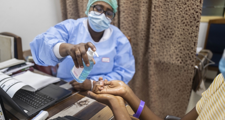 Midwife Rebecca Kpabitey Maame provides hand sanitizer to Maame Kesewa Akuamah, who delivered her baby Ishod at Greater Accra Regional Hospital in June, and is now bringing him for a postnatal visit.