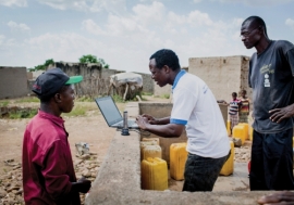 An official checks data from an internet-based water monitoring device at a borehole in Basbedo, Burkina Faso. Photo: Panos/Andrew McConnell