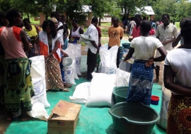 People gather at Mikolongo school in Chikwawa district, Malawi, to receive rations of maize, pulses, oil and fortified corn soya blend from WFP to prevent malnutrition. 