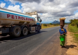 A Tanzanian woman walks to the market as a petrol lorry passes by. Photo: Alamy /Wietse Michiels Travel Stock