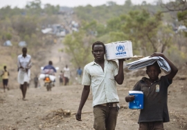 Des réfugiés sud-soudanais avec des articles de secours dans le site pour réfugiés de Bidibidi, en Ouganda. Photo HCR/David Azia