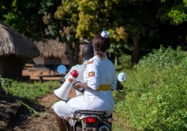 Ugandan healthcare worker on motorcycle with megaphone.