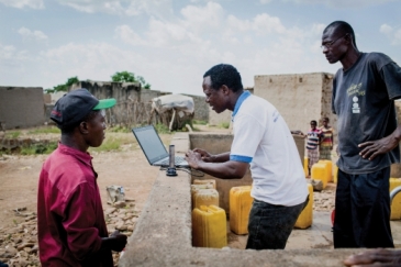 An official checks data from an internet-based water monitoring device at a borehole in Basbedo, Burkina Faso. Photo: Panos/Andrew McConnell