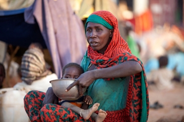 A displaced mother prepares food for her child outside the UNAMID base in Um Baru, North Darfur. UN Photo/Hamid Abdulsalam