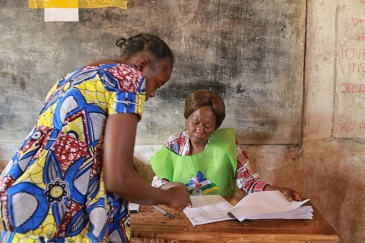 In Bangui on 14 February 2016, an electoral officer (right) assists a voter at a polling station for the Central African Republic’s run-off presidential elections. A re-run of the 30 December 2015 legislative elections was also held. UN Photo/Nektarios Ma