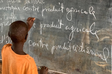 A young Burundian refugee completes an exercise on a blackboard in Nyarugusu Refugee Camp, Tanzania.