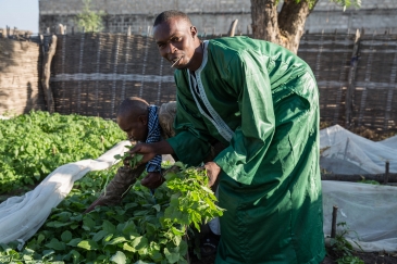 Ibrahima Sow, a Senegalese returnee, dressed up to show his work as a market gardener.