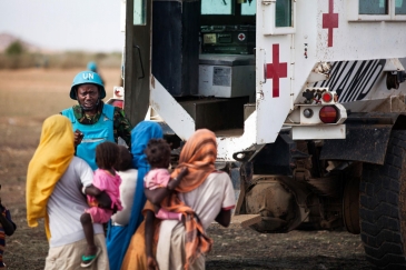 Un Casque bleu de la MINUAD avec des enfants dans le village de Karbab, au Sud-Darfour, lors d’une patrouille de routine. Photo ONU/Albert Gonzalez Farran