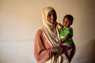 Hayat stands with her child who is being treated for malnutrition 