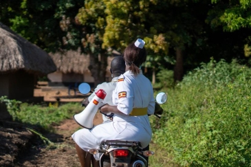 Ugandan healthcare worker on motorcycle with megaphone.