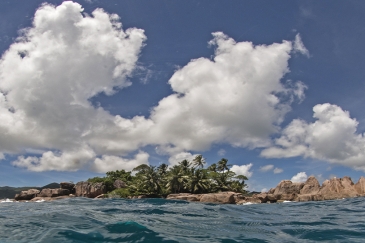 Island with water in foreground and blue sky above.