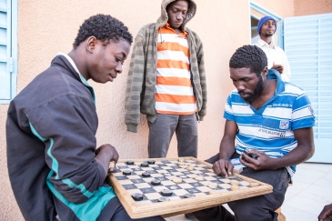 Migrants play a board game at IOM Transit Center in Agadez, Niger (2016).