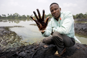 Claimant Eric Dooh shows the crude oil that has damaged the banks of the creek through his village in Ogoniland, Nigeria. 