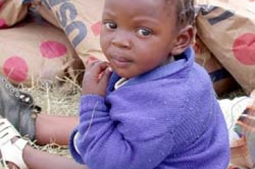 Un enfant assis parmi des sacs de céréales envoyés d'urgence au Lesotho. Photo : ©PAM / R. Lee