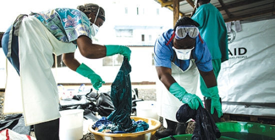 Health workers clean hospital scrubs and protective gear at the Island Clinic for Ebola treatment centre in Monrovia, Liberia, during the 2014 Ebola outbreak.   USAID/Morgana Wingard