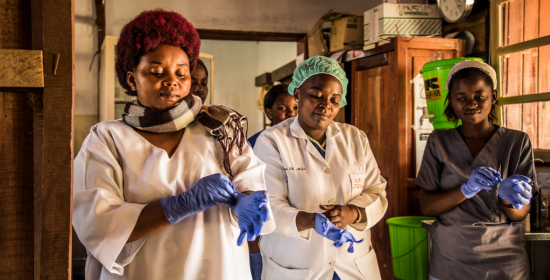 Health workers in the DRC put on gloves on before checking patients at the hospital.