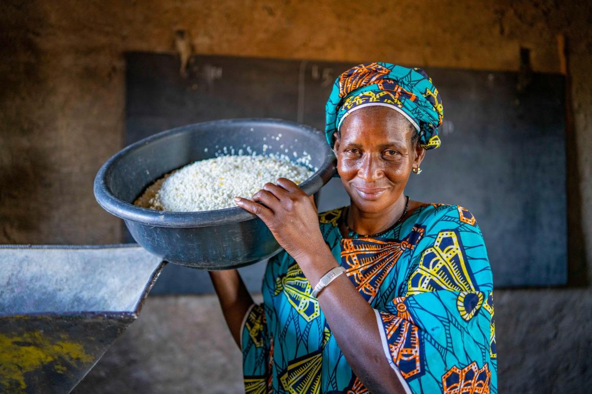 A woman holding a bowl of crops from the community empowerment activity in Mali