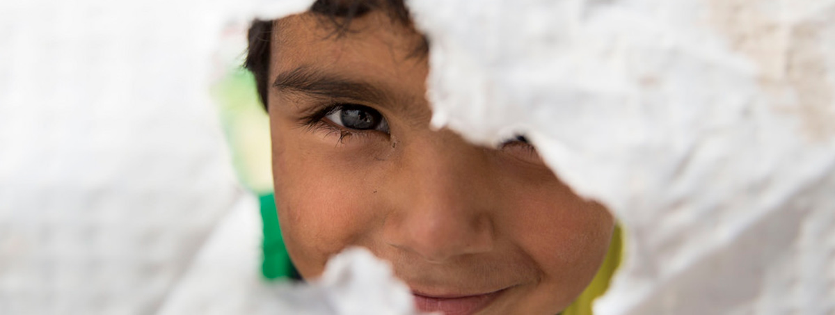 Child peering through a hole in a canvas wall