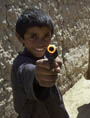 Boys playing with toy guns run into a village alley in Bagram, Afghanistan (UN Eric Kanalstein)