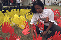An indigenous Australian adolescent girl plants painted hand cut-outs in the ground, during the 2001 conference -UNICEF/HQ01-0330/Giacomo Pirozzi