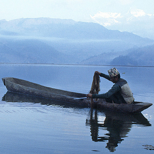 A fisherman on a canoe fishing in Lake Fewa, Nepal.