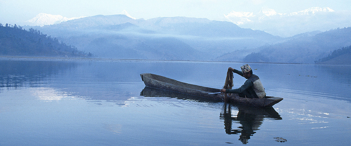 A fisherman on a canoe fishing in Lake Fewa, Nepal.