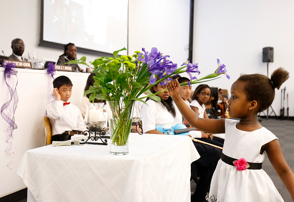 A young girl honoures the victims of genocide with a flower.