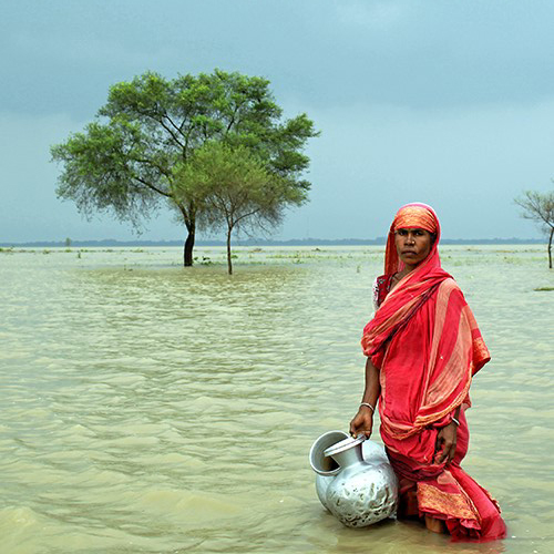 Mujer de Bangladesh en un lago sosteniendo unas cántaras de agua.
