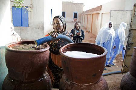 Una mujer llenando un recipiento con agua