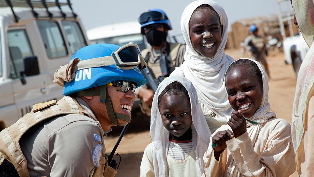 Le lieutenant-colonel Yenni Windarti, de la police civile indonésienne, agent de maintien de la paix de la MINUAD, interagit avec des femmes et des enfants à un point d’eau du camp de personnes déplacées d’Abu Shouk (Darfour Nord) au cours d’une patrouille matinale. Photo : ONU/Albert González Farran