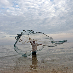 Au Timor Leste, un pêcheur jette un filet dans l’eau pour attraper des petits poissons.