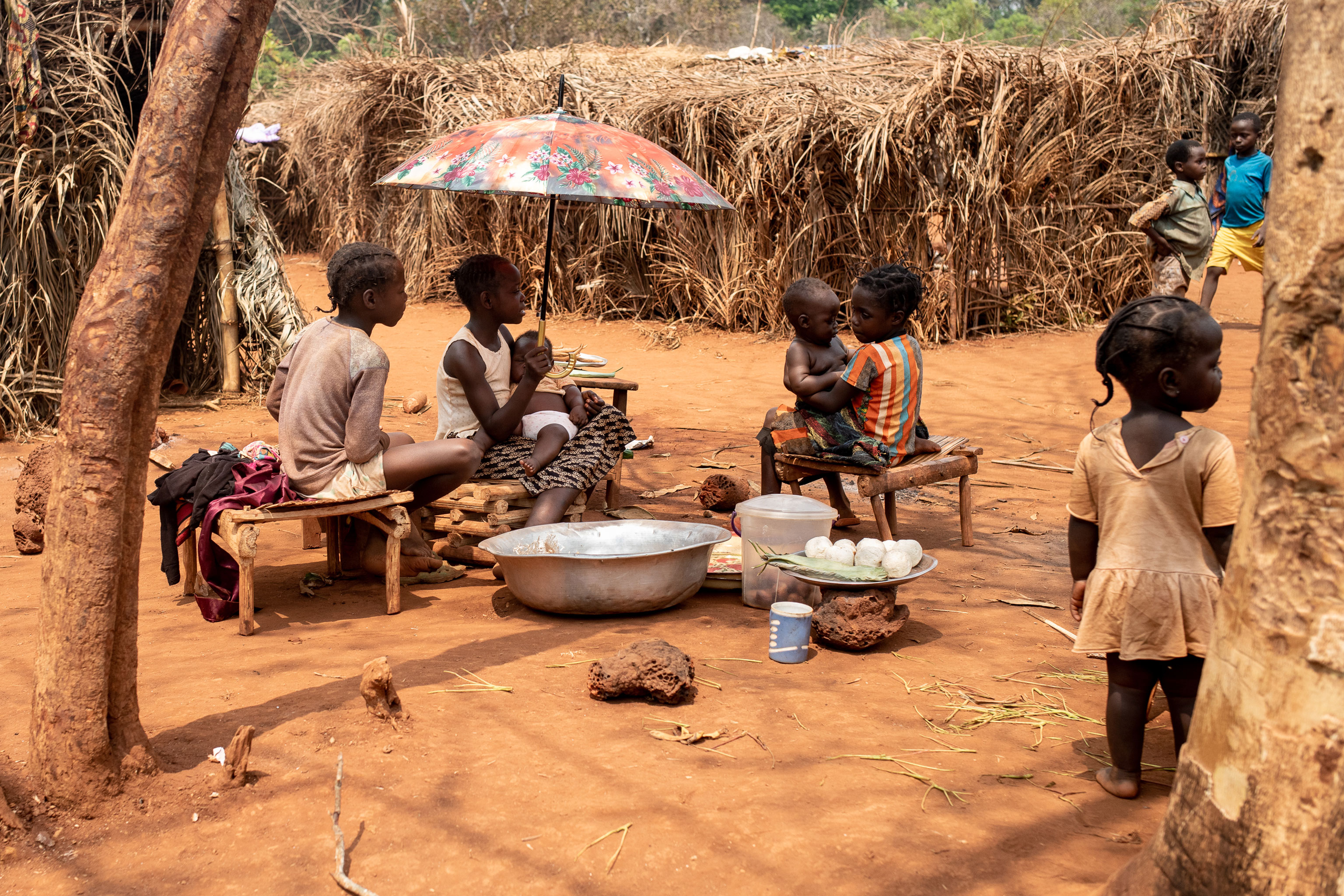 De jeunes enfants assis dans une zone aride avec de la nourriture à vendre.