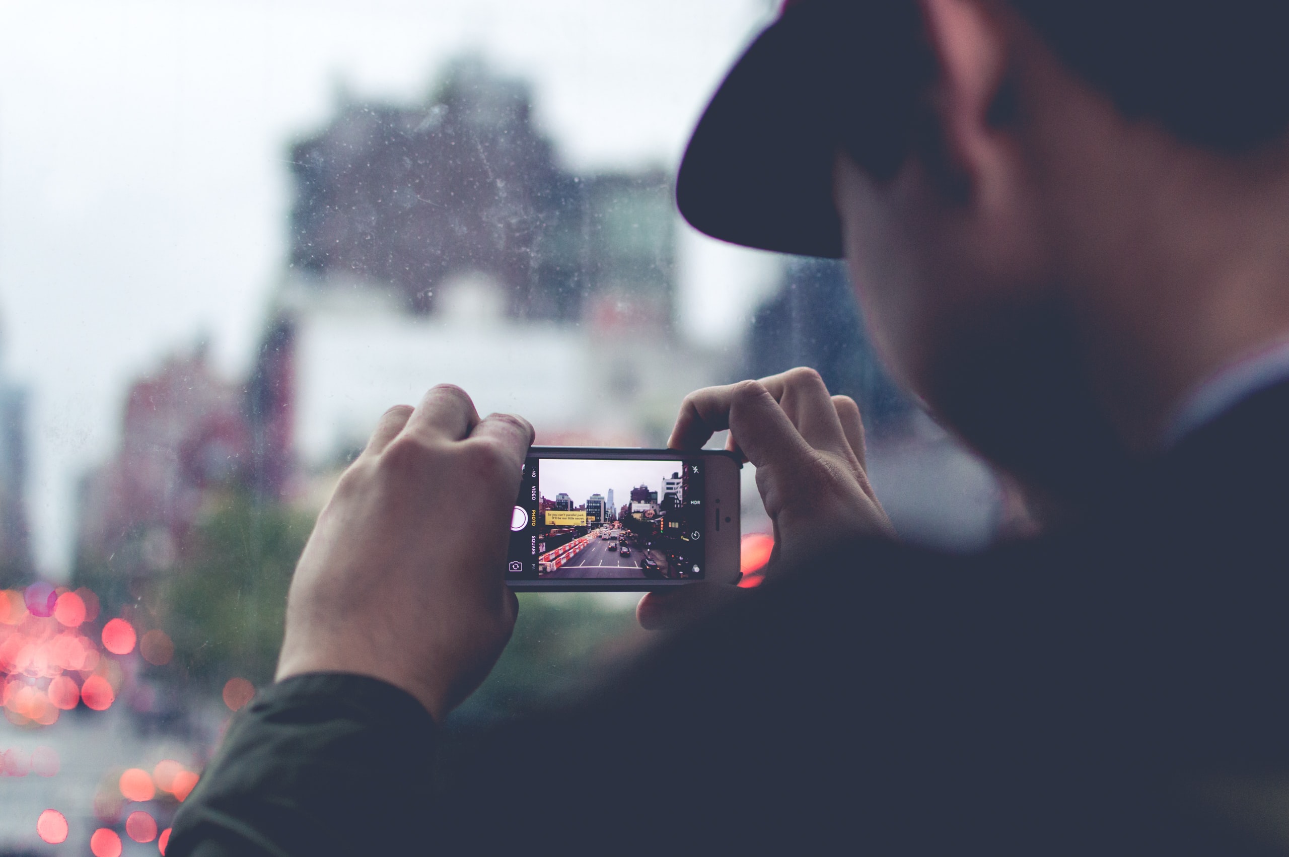 Un homme prend une photo d'un paysage urbain avec son téléphone.
