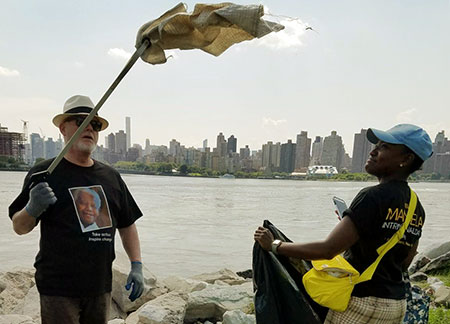 Deux membres du personnel de l'ONU en train de nettoyer les rives et retirer les plantes envahissantes autour du port