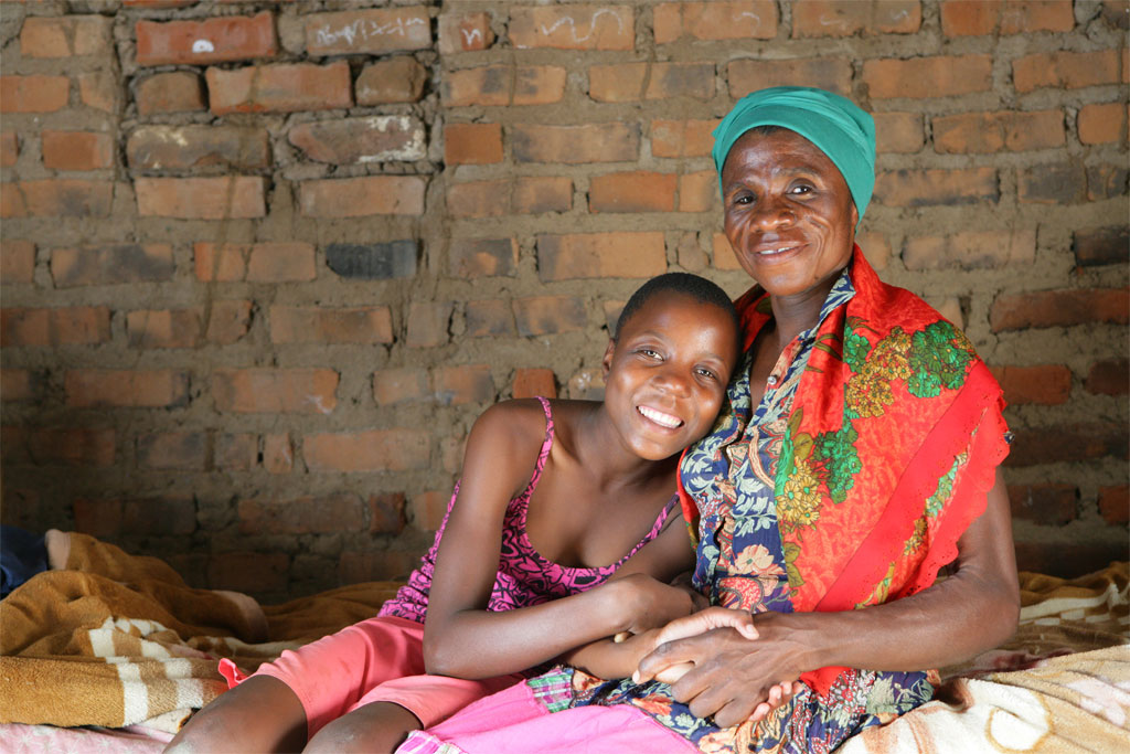 An older woman sits down with a younger girl.