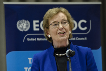 Mary Robinson is wearing a black shirt and blue blazer and is speaking into a microphone. Behind her is a sign stating ‘ECOSOC.’