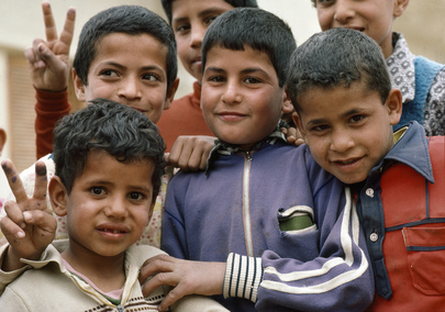 Six young Palestinian wave at a camera.