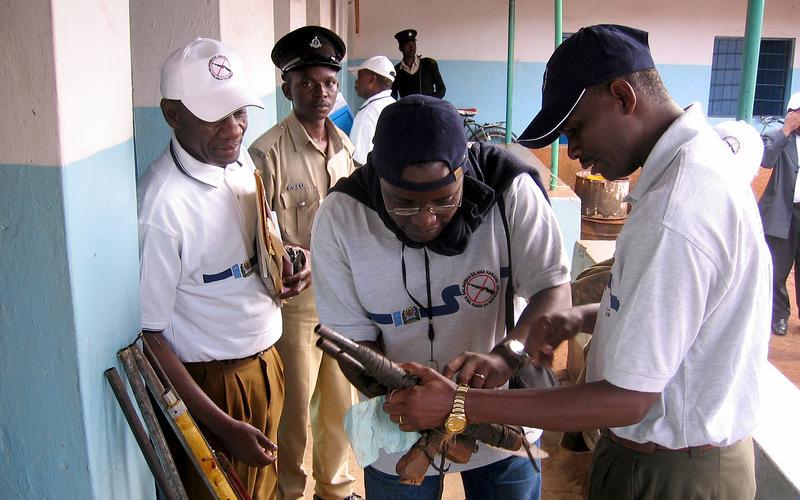 A group of men are closely examining guns.