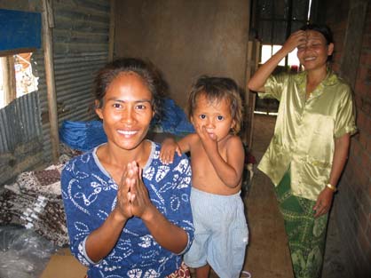 Two young women and a child stand in a small dark room. Aluminium sheets are covering the windows.