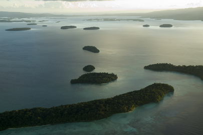 An aerial shot of a lagoon in the Solomon Islands at sunrise. There are several islands scattered throughout the lagoon.