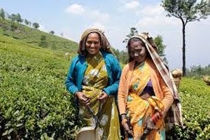 Two women dressed in colourful clothing stand in a mountainous field.