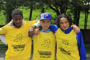 Three boys stand with their arms around each other.