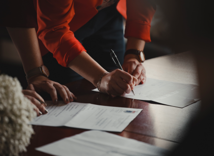 Person signing a form with a pen