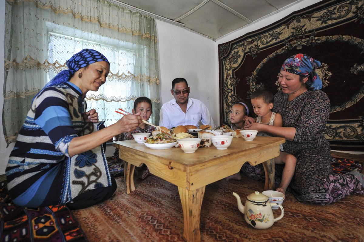 Una familia disfruta de una comida juntos alrededor de una mesa en su casa en un pueblo de Kirguistán.