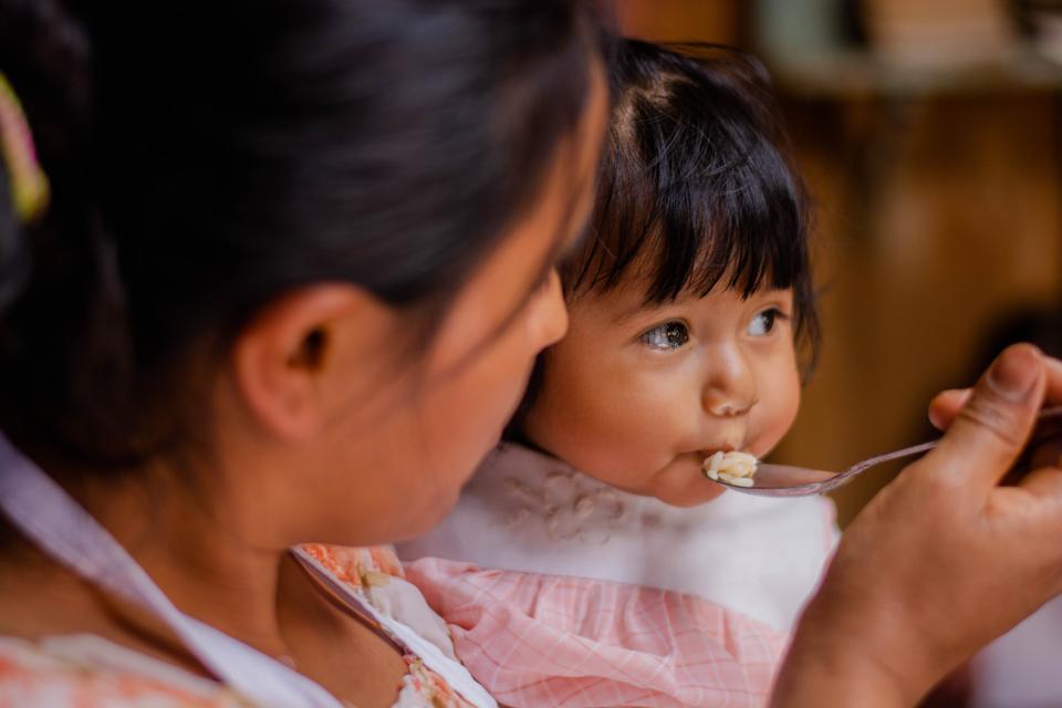 Una madre guatemalteca da a su pequeña una cucharada de arroz. 