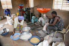 A woman and man process corn using the multifunctional platform engine in Burkina Faso.