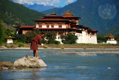 A man removes a plastic bottle from a river in Punakha, Bhutan