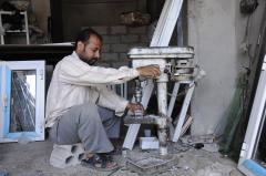 Worker at aluminum shop makes window frames in Yemen.