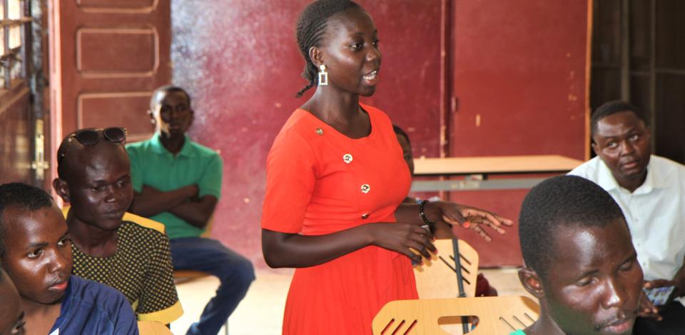 Woman in green dress speaking at a peacebuilding meeting