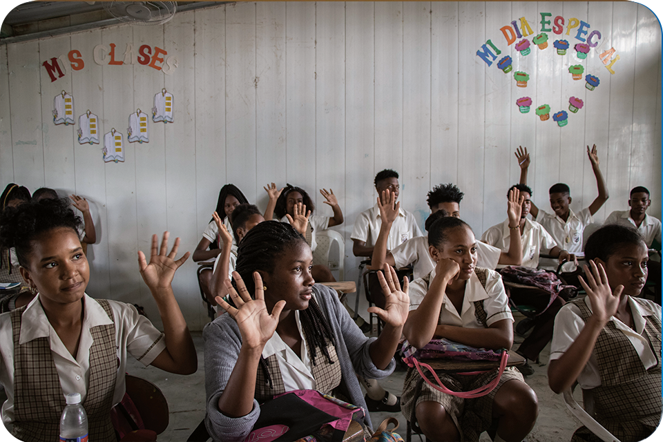 Group of participants in class with hands raised to answer questions